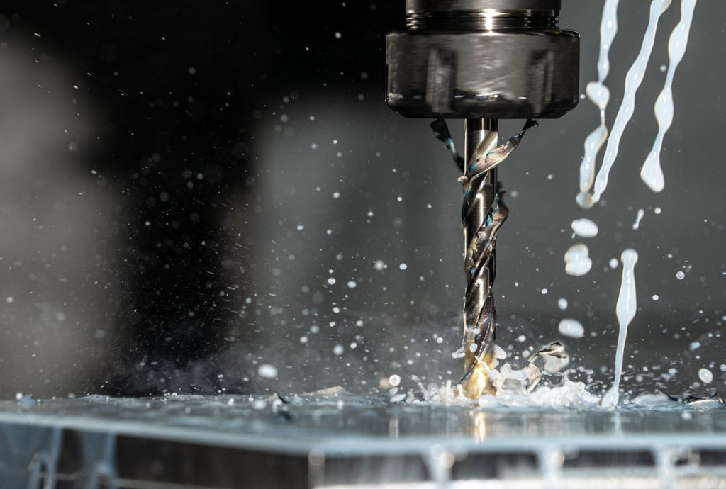 pexels-photo-8956313 High-speed close-up of CNC drill bit in action with water splash for lubrication.